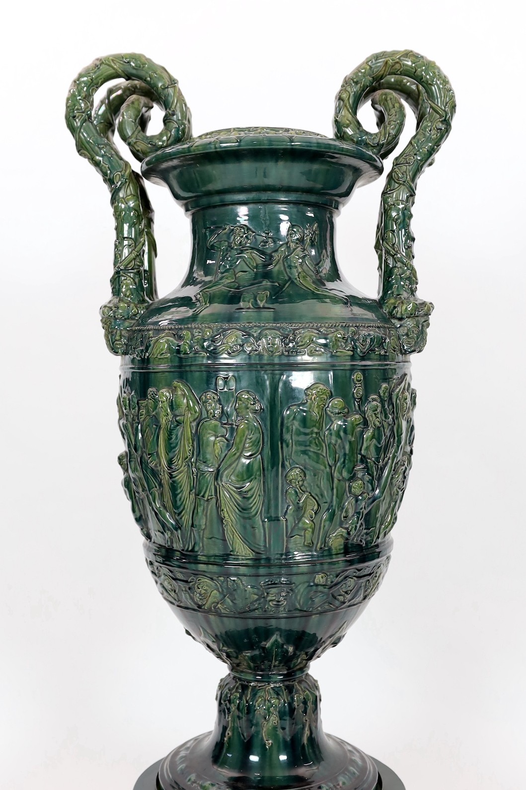 A massive Continental majolica green glazed campana vase and associated stand, late 19th century, total height 153cm, small repairs